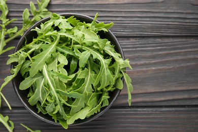 Photo of Fresh ripe green arugula leaves on dark wooden table, top view. Space for text