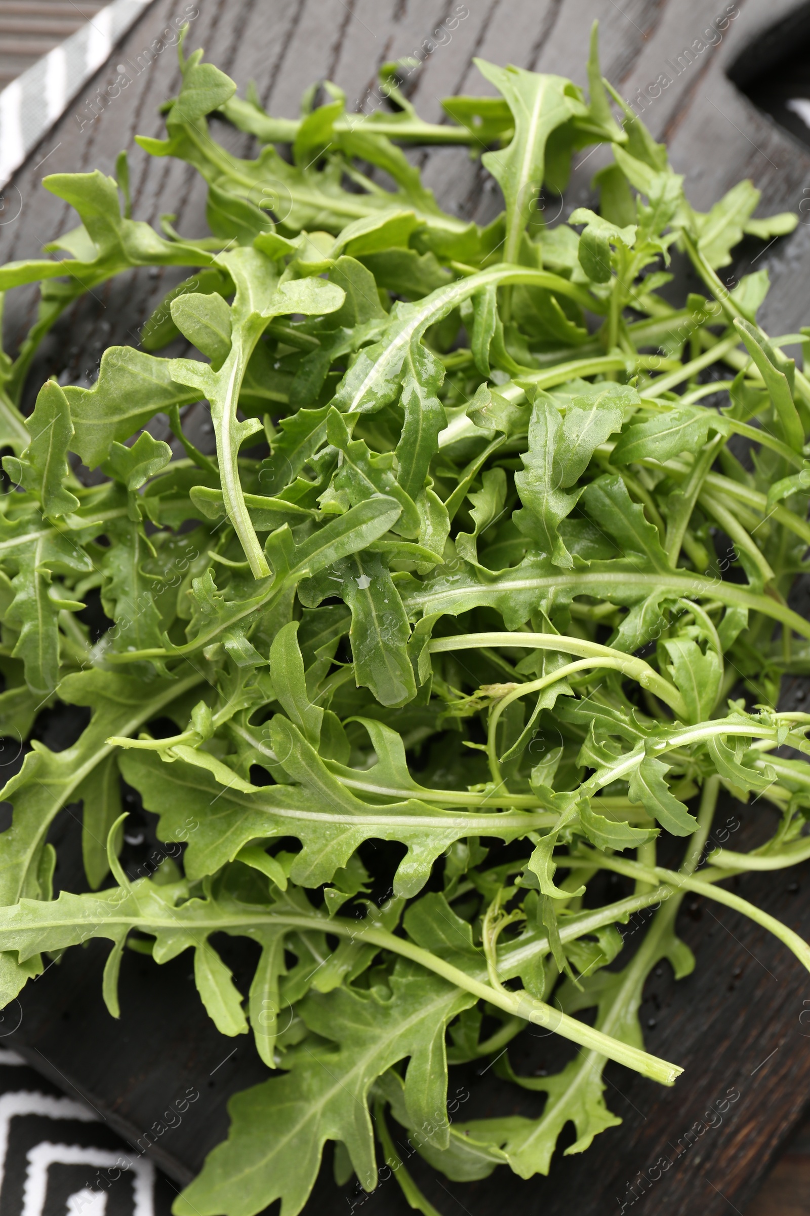 Photo of Fresh ripe green arugula leaves on dark wooden table, top view