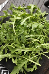 Photo of Fresh ripe green arugula leaves on dark wooden table, top view
