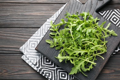 Photo of Fresh ripe green arugula leaves on dark wooden table, top view