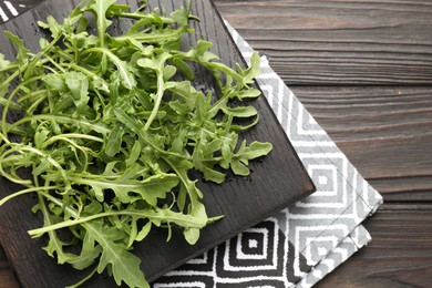 Photo of Fresh ripe green arugula leaves on dark wooden table, top view