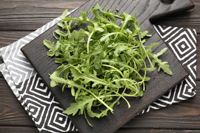 Photo of Fresh ripe green arugula leaves on dark wooden table, top view