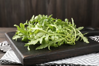Photo of Fresh ripe green arugula leaves on dark wooden table, closeup