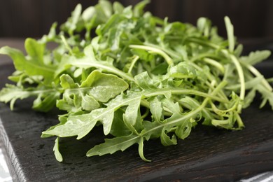 Photo of Fresh ripe green arugula leaves on dark wooden table, closeup