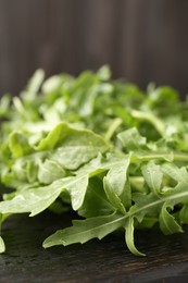 Photo of Fresh ripe green arugula leaves on dark wooden table, closeup