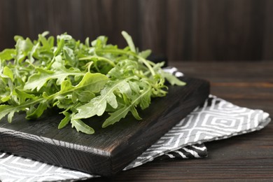 Photo of Fresh ripe green arugula leaves on dark wooden table, closeup
