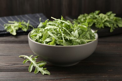 Photo of Fresh ripe green arugula leaves on dark wooden table, closeup