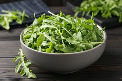 Photo of Fresh ripe green arugula leaves on dark wooden table, closeup
