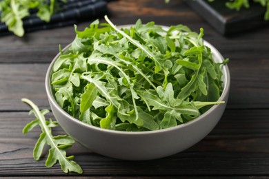 Photo of Fresh ripe green arugula leaves on dark wooden table, closeup