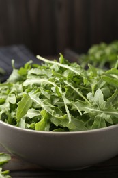 Photo of Fresh ripe green arugula leaves on dark wooden table, closeup