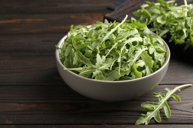 Photo of Fresh ripe green arugula leaves on dark wooden table, closeup
