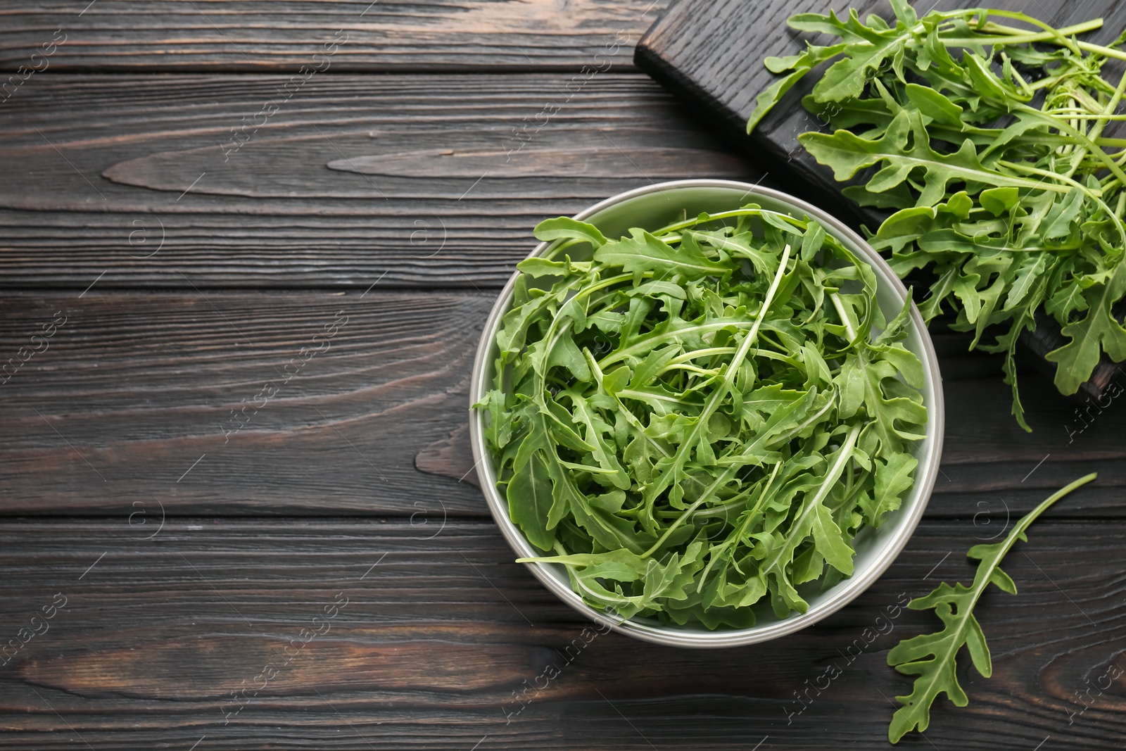 Fresh ripe green arugula leaves on dark wooden table, flat lay. Space for text Photo of Fresh ripe green arugula leaves on dark wooden table, flat lay. Space for text
