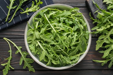 Photo of Fresh ripe green arugula leaves on dark wooden table, flat lay