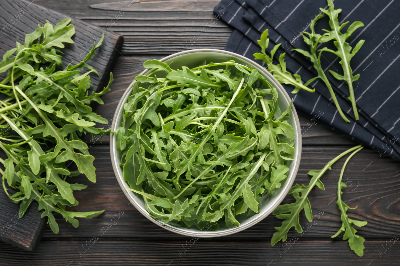 Fresh ripe green arugula leaves on dark wooden table, flat lay Photo of Fresh ripe green arugula leaves on dark wooden table, flat lay