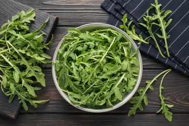Photo of Fresh ripe green arugula leaves on dark wooden table, flat lay