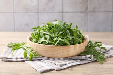 Photo of Fresh ripe green arugula leaves on light wooden table, closeup