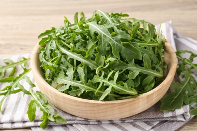 Photo of Fresh ripe green arugula leaves on light wooden table, closeup