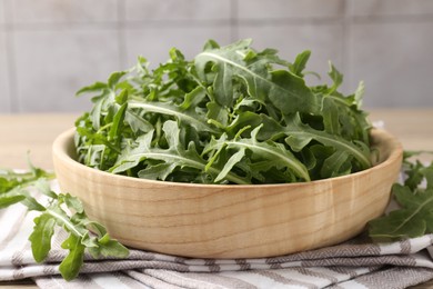 Photo of Fresh ripe green arugula leaves on light wooden table, closeup