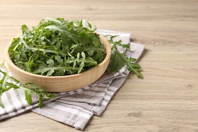 Photo of Fresh ripe green arugula leaves on light wooden table, closeup. Space for text