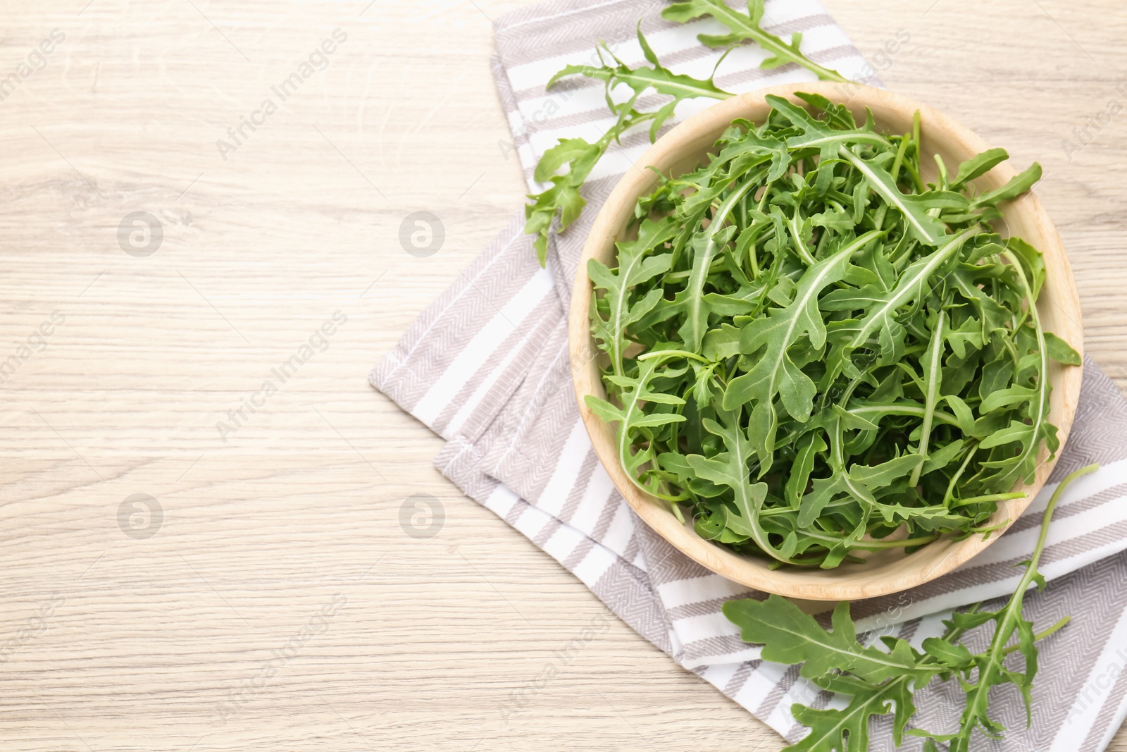 Fresh ripe green arugula leaves on light wooden table, flat lay. Space for text Photo of Fresh ripe green arugula leaves on light wooden table, flat lay. Space for text