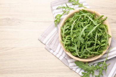 Photo of Fresh ripe green arugula leaves on light wooden table, flat lay. Space for text