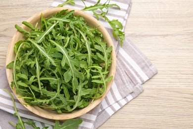 Photo of Fresh ripe green arugula leaves on light wooden table, flat lay. Space for text