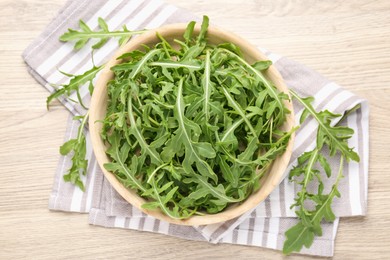 Photo of Fresh ripe green arugula leaves on light wooden table, flat lay