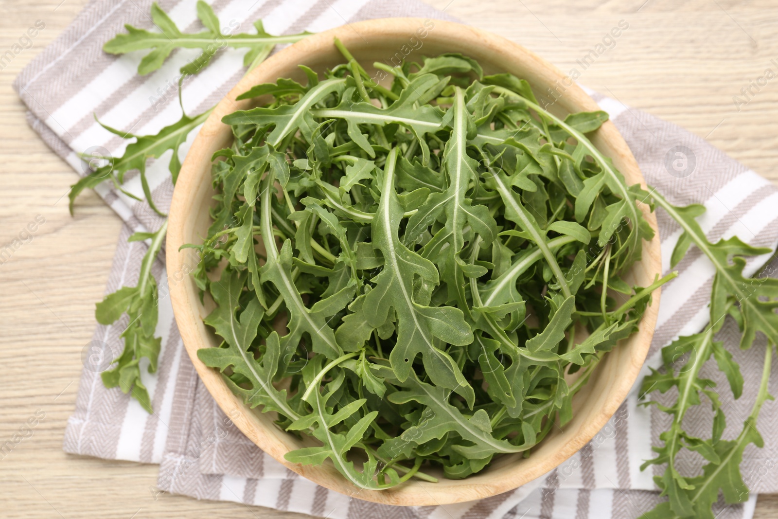 Fresh ripe green arugula leaves on light wooden table, flat lay Photo of Fresh ripe green arugula leaves on light wooden table, flat lay