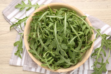 Photo of Fresh ripe green arugula leaves on light wooden table, flat lay