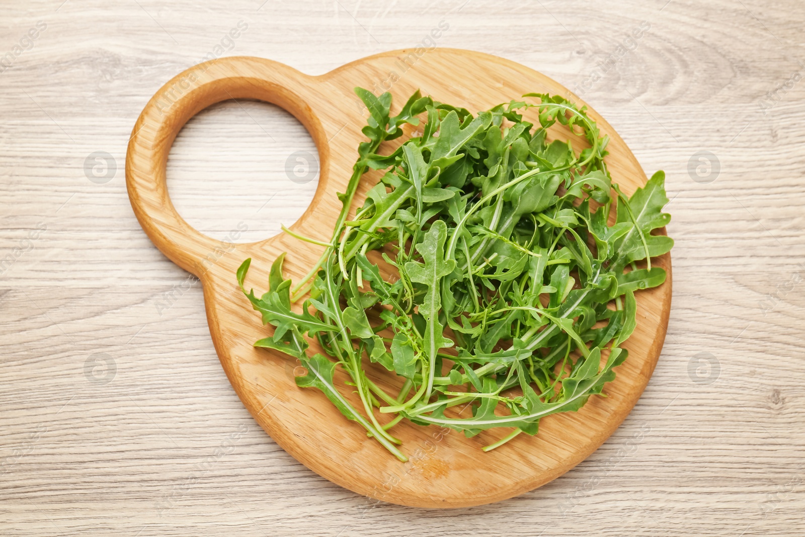 Fresh ripe green arugula leaves on light wooden table, top view Photo of Fresh ripe green arugula leaves on light wooden table, top view
