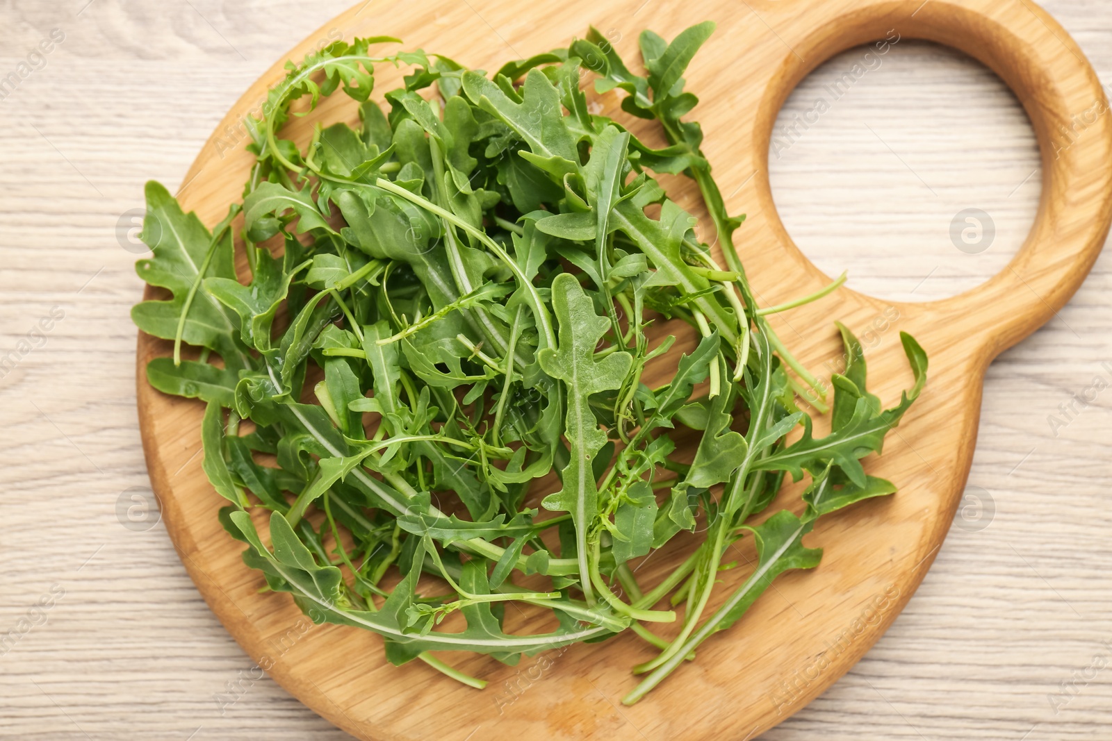 Fresh ripe green arugula leaves on light wooden table, top view Photo of Fresh ripe green arugula leaves on light wooden table, top view