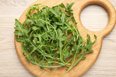 Photo of Fresh ripe green arugula leaves on light wooden table, top view