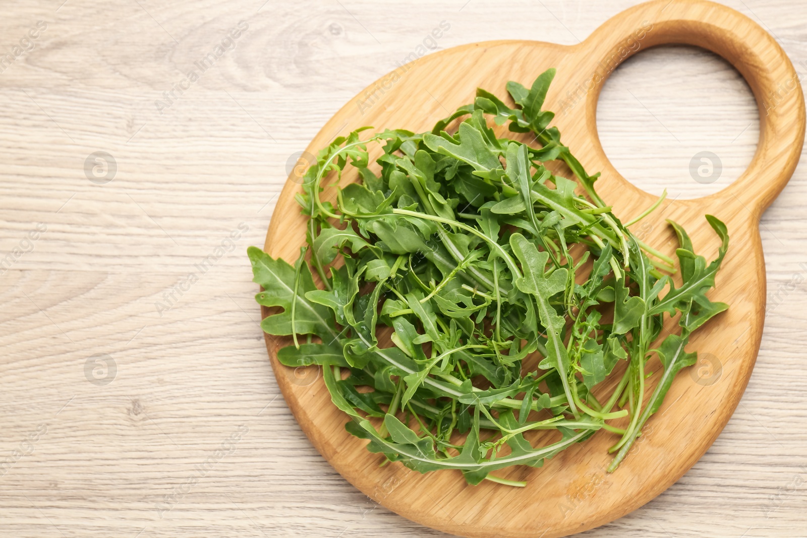 Fresh ripe green arugula leaves on light wooden table, top view. Space for text Photo of Fresh ripe green arugula leaves on light wooden table, top view. Space for text
