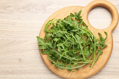 Photo of Fresh ripe green arugula leaves on light wooden table, top view. Space for text