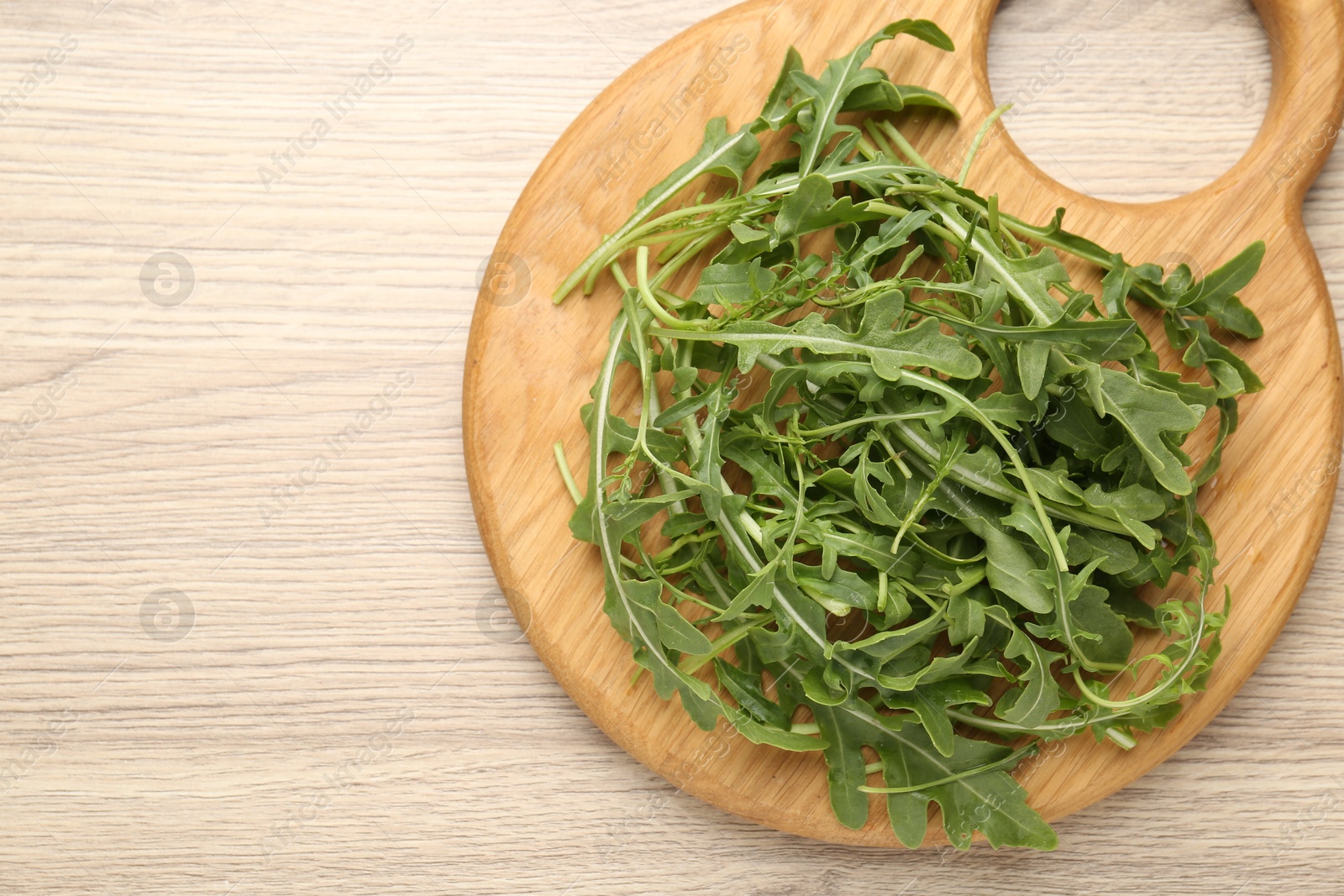 Fresh ripe green arugula leaves on light wooden table, top view. Space for text Photo of Fresh ripe green arugula leaves on light wooden table, top view. Space for text