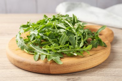 Photo of Fresh ripe green arugula leaves on light wooden table, closeup