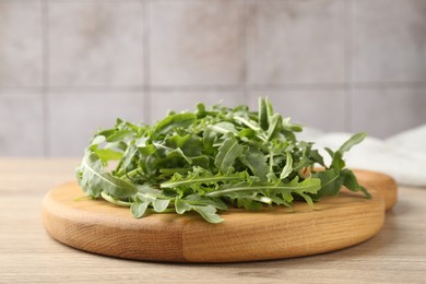 Photo of Fresh ripe green arugula leaves on light wooden table, closeup