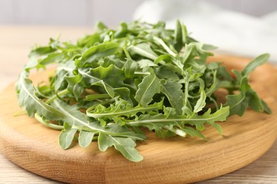Photo of Fresh ripe green arugula leaves on light wooden table, closeup