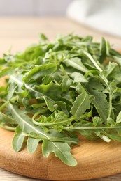 Photo of Fresh ripe green arugula leaves on light wooden table, closeup