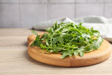 Photo of Fresh ripe green arugula leaves on light wooden table, closeup