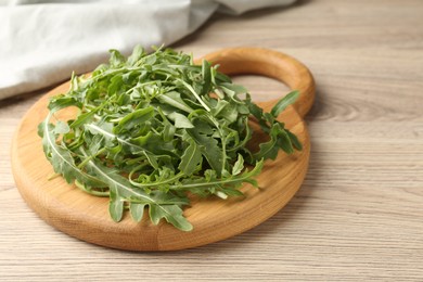 Photo of Fresh ripe green arugula leaves on light wooden table, closeup