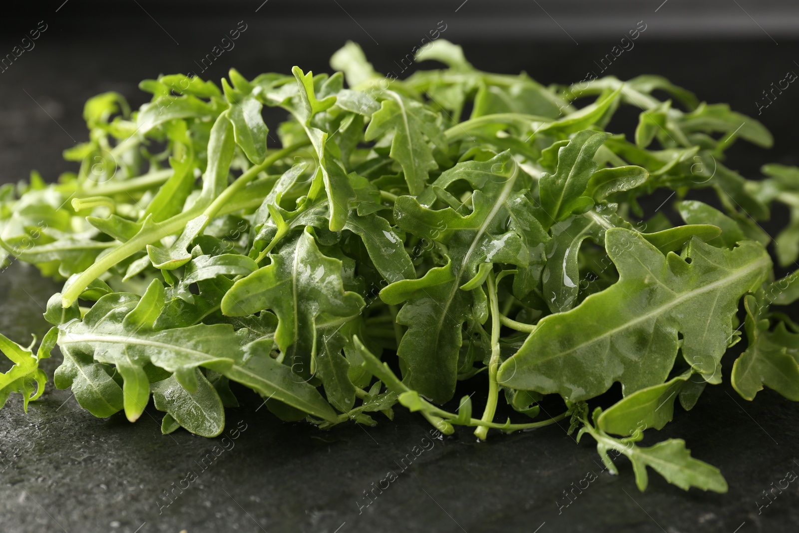 Fresh ripe green arugula leaves on black table, closeup Photo of Fresh ripe green arugula leaves on black table, closeup