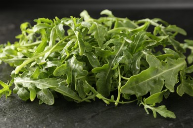 Photo of Fresh ripe green arugula leaves on black table, closeup