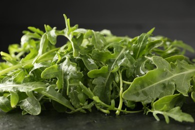 Photo of Fresh ripe green arugula leaves on black table, closeup