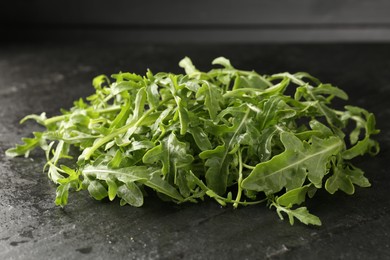 Photo of Fresh ripe green arugula leaves on black table, closeup