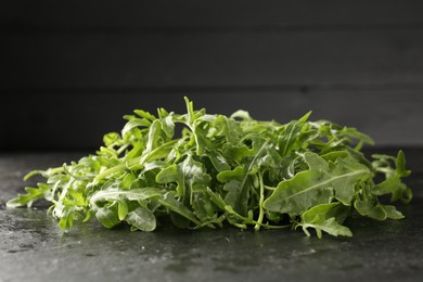 Photo of Fresh ripe green arugula leaves on black table, closeup