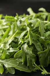 Photo of Fresh ripe green arugula leaves on black background, closeup