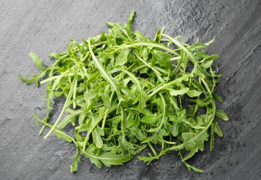 Photo of Fresh ripe green arugula leaves on black table, top view
