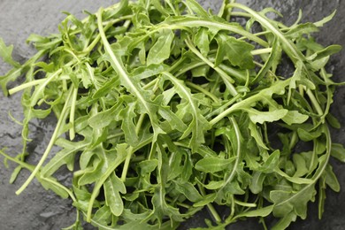 Photo of Fresh ripe green arugula leaves on black table, top view