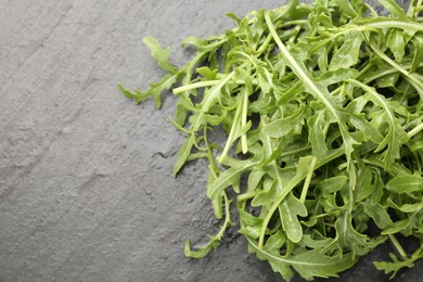 Photo of Fresh ripe green arugula leaves on black table, top view. Space for text